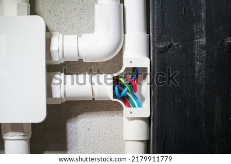 Electrician open cap of PVC inspection tee fitting on wall
