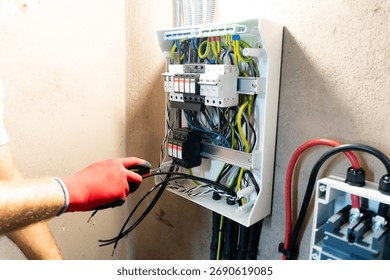 Electrician performing maintenance or installation work inside an electrical panel, ensuring safety and proper electrical connection.