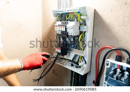 Electrician performing maintenance or installation work inside an electrical panel, ensuring safety and proper electrical connection.
