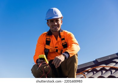 Electrician With Power Meter On House Roof On A Sunny Day