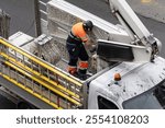 Electrician preparing christmas lights for installation on city street using a crane truck