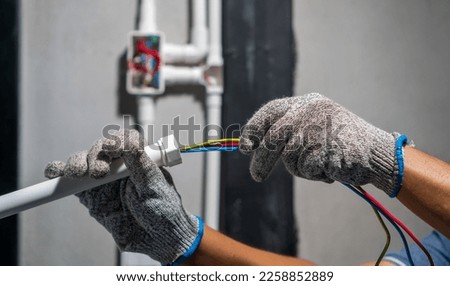 Electrician pulling wire into PVC Conduit.