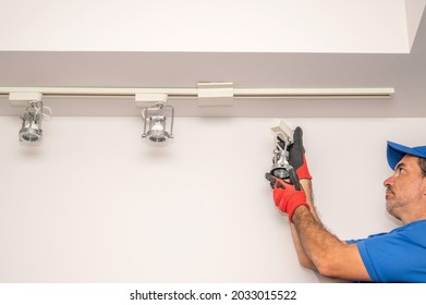 Electrician Removing A Track Lighting Fixture From The Ceiling