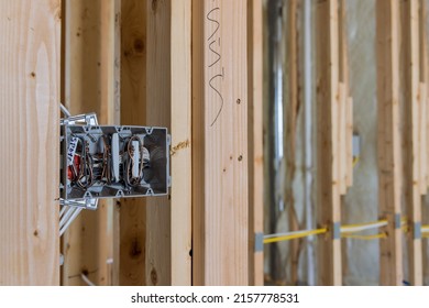 Electrician routing wires in electric plug connector, electric sockets on the wall inside a wooden beams frame house
