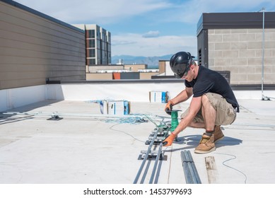 Electrician Running Wire Through Conduit On A Building Roof Top.