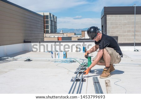 Electrician running wire through conduit on a building roof top.