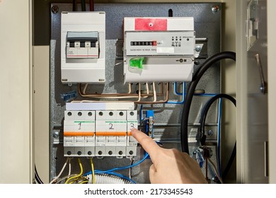 Electrician switches circuit breaker in consumer unit of fuse box and electric meter. - Shutterstock ID 2173345543