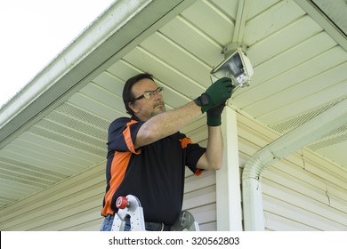 Electrician Taking Defective Bulb Out Of Outside Light Fixture.