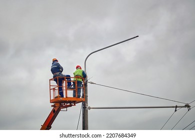 Electrician Team Improve Old Street Lamp. Street Light Repair Works, Workers Repair Street Lamp At Height, Led Lights Replacement. Men In Lift Bucket Wearing Personal Protective Equipment