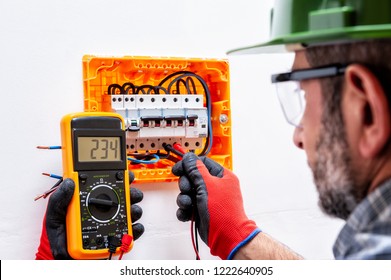 Electrician Technician With Helmet, Goggles And Hands Are Protected By Gloves Measure The Voltage In A Residential Electrical Panel.