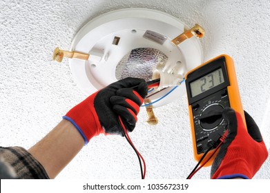 Electrician technician measures the voltage in the lamp socket of a residential electrical system