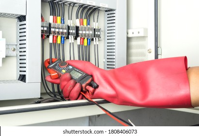 Electrician Technician Using Digital Camp Amp Meter To Check Electric Current In A Factory  Electrical Installation With  Hands Protected By Electric Hand Gloves