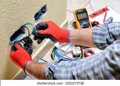 Electrician technician at work sticks the cable between the clamps of a socket in a residential electrical installation
