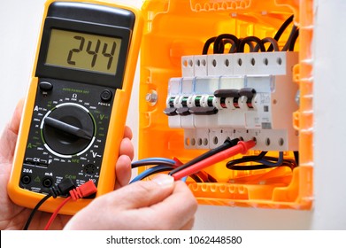 Electrician Technician Working On A Residential Electrical Panel, Measures The Voltage On The Terminals Of The Thermal Magnetic Circuit Breaker