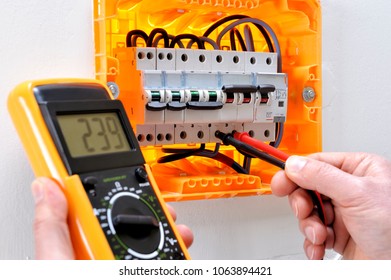 Electrician Technician Working On A Residential Electrical Panel, Measures The Voltage On The Terminals Of The Thermal Magnetic Circuit Breaker