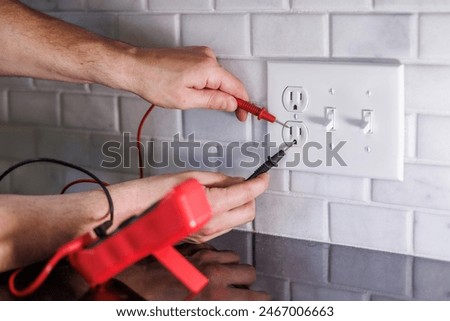 Electrician testing electrical outlet with multimeter