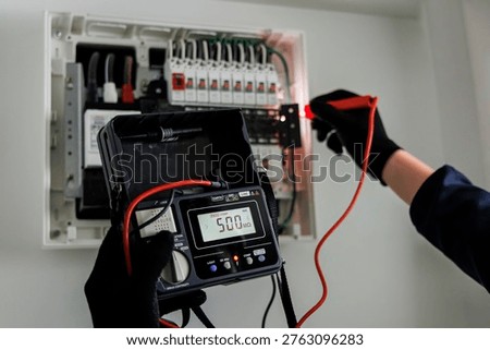 Electrician Testing Electrical Panel with Digital Insulation Resistance Tester Showing 500M Ohms Reading - Safety Inspection, Periodic Maintenance and Facility Management Concept