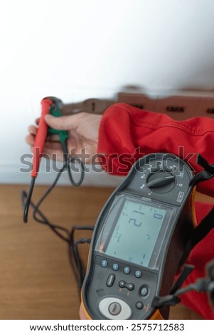 Electrician tests socket voltage with a specialized device, ensuring safety and proper functionality. High quality photo