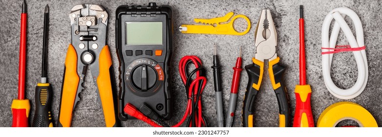 Electrician tools on black marble background.Multimeter,construction tape,electrical tape, screwdrivers,pliers,an automatic insulation stripper, socket and LED lamp.Flatley.electrician concept.