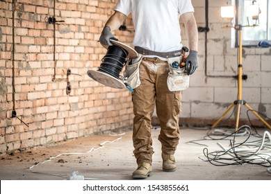 Electrician with tools, working on a construction site. Repair and handyman concept. House and house reconstruction.