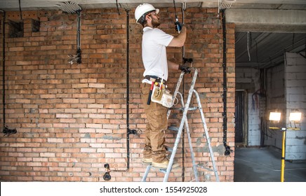 Electrician with tools, working on a construction site. Repair and handyman concept. House and house reconstruction.