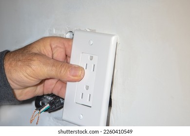 Electrician trying on a socket before repairing a wall