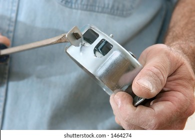 An electrician using a screwdriver to remove the knock-outs (tabs) from an electrical box.  Work is being performed according to code by a licensed master electrician.