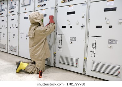 The electrician wear arc flash suit, electrical safety gloves and high voltage insulating boots to open power compartment door for rackout circuit breaker of medium voltage switchgear