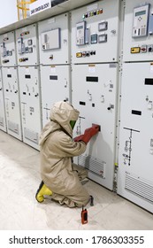 The Electrician Wear Arc Flash Suit, Electrical Safety Gloves And High Voltage Insulating Boots To Opening For Switching-device Track Operation Of Circuit Breaker Panel