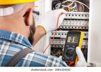 Electrician At Work On An Electrical Panel Protected In Safety Goggles And Gloves; Coronavirus. Construction Industry. Covid 19 Prevention.