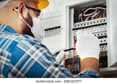 Electrician At Work On An Electrical Panel Protected In Safety Goggles And Gloves; Coronavirus. Construction Industry. Covid 19 Prevention.