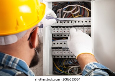 Electrician At Work On An Electrical Panel Protected In Safety Goggles And Gloves; Coronavirus. Construction Industry. Covid 19 Prevention.