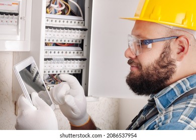 Electrician At Work On An Electrical Panel Protected In Safety Goggles And Gloves; Coronavirus. Construction Industry. Covid 19 Prevention.