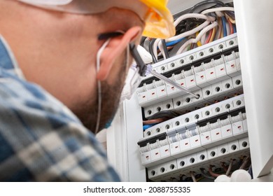 Electrician At Work On An Electrical Panel Protected In Safety Goggles And Gloves; Coronavirus. Construction Industry. Covid 19 Prevention.