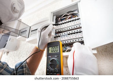 Electrician At Work On An Electrical Panel Protected In Safety Goggles And Gloves; Coronavirus. Construction Industry. Covid 19 Prevention.