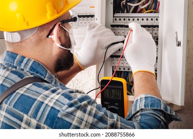 Electrician At Work On An Electrical Panel Protected In Safety Goggles And Gloves; Coronavirus. Construction Industry. Covid 19 Prevention.