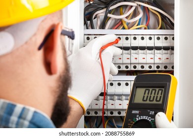 Electrician At Work On An Electrical Panel Protected In Safety Goggles And Gloves; Coronavirus. Construction Industry. Covid 19 Prevention.