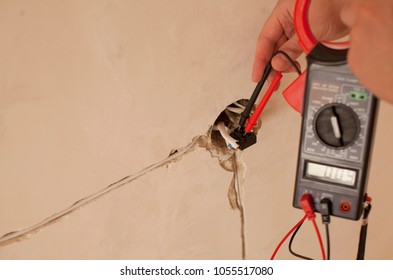 Electrician At Work On Switches And Sockets Of A Residential Electrical System. Young Electrician Measuring Voltage