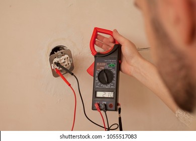 Electrician At Work On Switches And Sockets Of A Residential Electrical System. Young Electrician Measuring Voltage