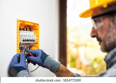 Electrician at work prepares electrical cables in the switchboard of a residential electrical system. Construction industry. 