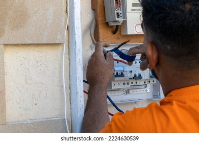 An Electrician At Work Repairs The Wiring In An Old House. The Master Changes The Electrical Panel. The Engineer Connects The Wires To The Fuses.