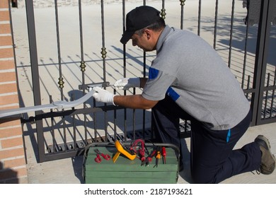 Electrician at work with tools of the trade while assembling and repairing the motor of an automatic gate. Do it yourself homework
				