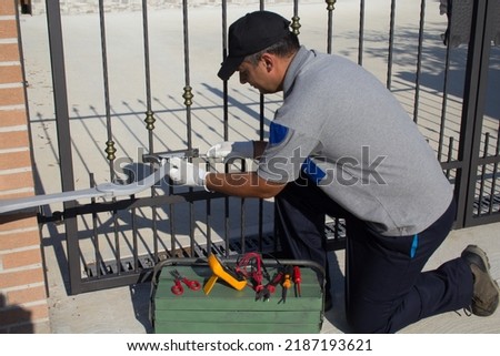Electrician at work with tools of the trade while assembling and repairing the motor of an automatic gate. Do it yourself homework
