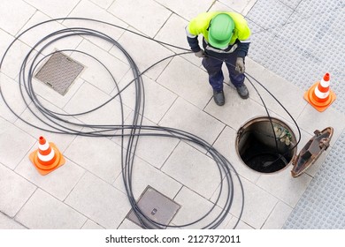 electrician worker install optical fiber cable for internet and telephone underground lines  in city street
