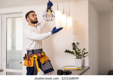 Electrician worker installation electric lamps light inside apartment. Construction decoration concept. - Shutterstock ID 2215168099