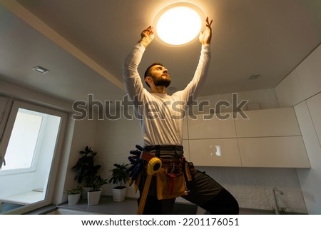 Electrician worker installation electric lamps light inside apartment. Construction decoration concept.