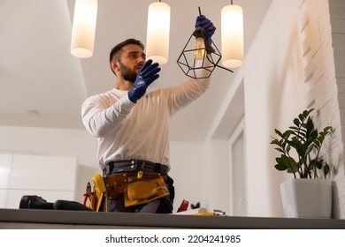 Electrician worker man assembling electric lamps in new apartment. - Shutterstock ID 2204241985
