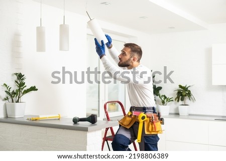 Electrician worker man assembling electric lamps in new apartment.