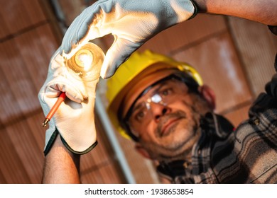 Electrician Worker At Work Replaces The Light Bulb In A Residential Electrical Installation. Construction Industry, Energy Sector. 