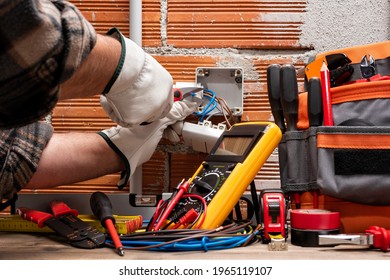 Electrician worker at work with scissors prepares the electrical cables of an electrical system. Working safely with protective gloves. Construction industry.